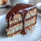 Tall slice of Hojicha Butter Cream Cake reveals soft sponge and rich dark chocolate ganache, served elegantly on a white dessert plate.