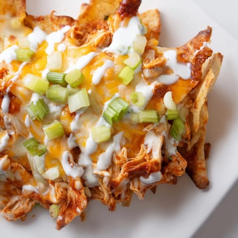 Hearty Buffalo Chicken Nachos piled high with fresh toppings, served hot and ready for game day snacking.  