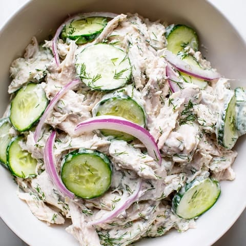 Tender shredded chicken and crisp cucumber slices coated in creamy dill yogurt dressing, served in a chilled salad bowl.  