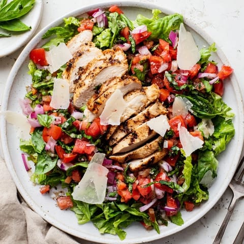 Juicy grilled chicken slices topped with fresh tomato basil bruschetta over crisp mixed greens for a light Italian salad.  