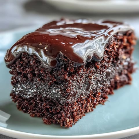 Easy Chocolate Fudge Cake is served warm on a rustic board, melting slightly alongside a tall glass of cold milk.