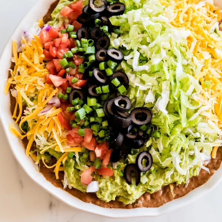 This photo depicts a beautifully arranged Seven-Layer Dip; a Tex-Mex delight perfect for sharing at parties.