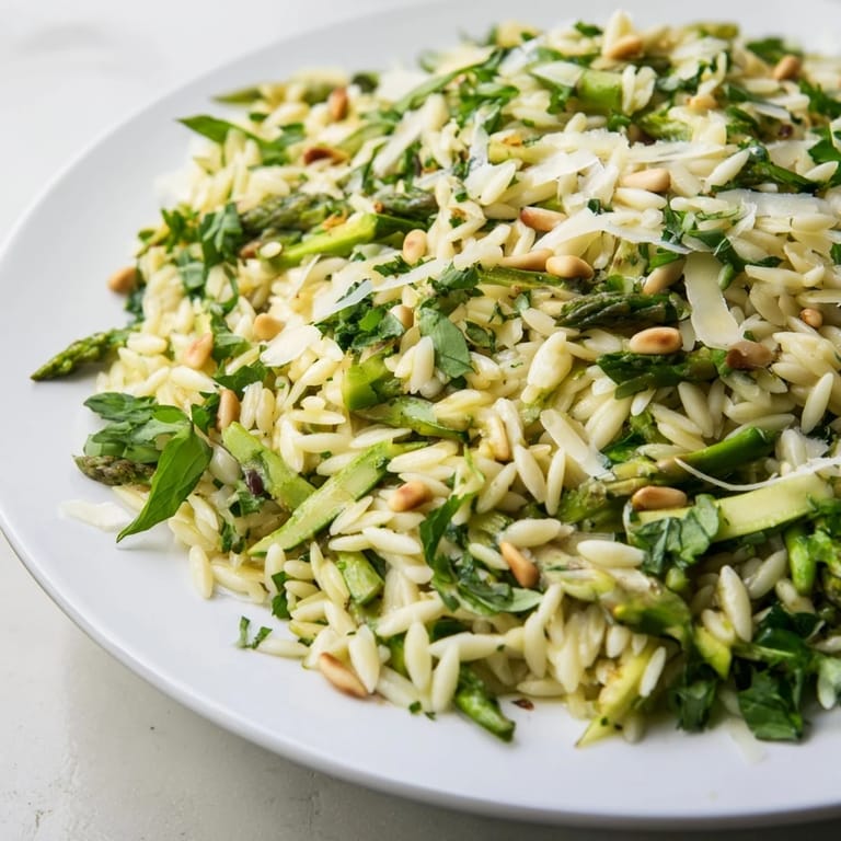 A close-up of a refreshing Mediterranean-style bowl, tossing al dente orzo with lemony dressing, shaved asparagus, and grated Parmesan, ideal for vegetarians seeking a quick and healthy side.
