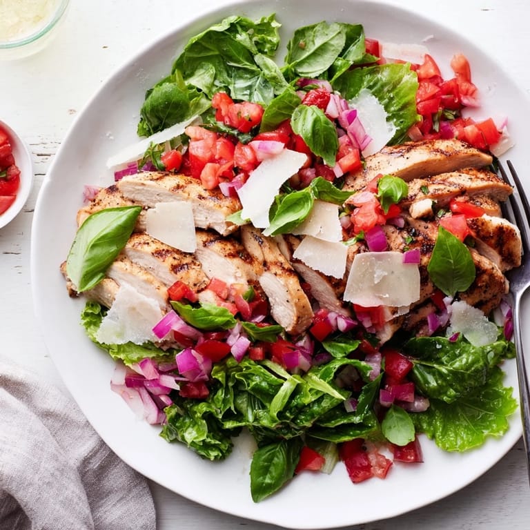 Bright, colorful Bruschetta Chicken Salad featuring tender chicken, ripe tomatoes, and shaved Parmesan on a bed of greens.  