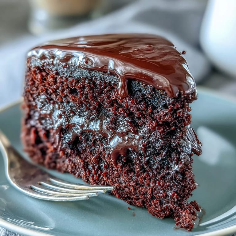 Homemade Easy Chocolate Fudge Cake features a rich, glossy ganache topping, ideal for a celebratory gathering or afternoon coffee break.