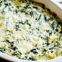 Creamy, bubbly Spinach Artichoke Dip, golden-brown on top, perfect with crackers and party guests.