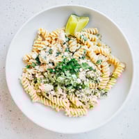 Creamy cilantro lime chicken pasta served in a white bowl with rotini, shredded chicken, and fresh cilantro garnish.