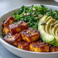 A vibrant Tofu Breakfast Bowl with avocado and kale, topped with golden, crispy tofu cubes and fresh lemon for squeezing.